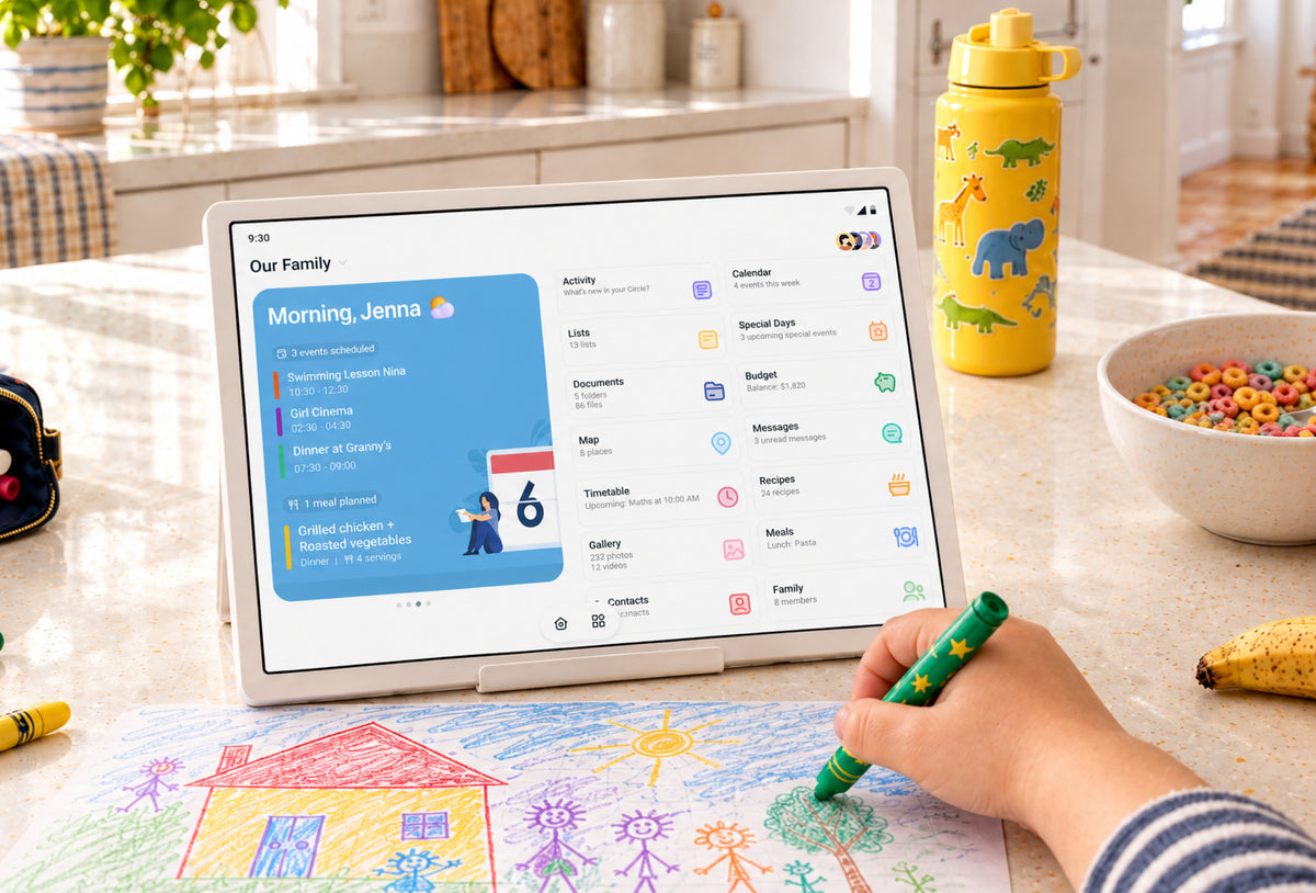 Home Hub on a kitchen counter showing the family home screen while a child colors beside it