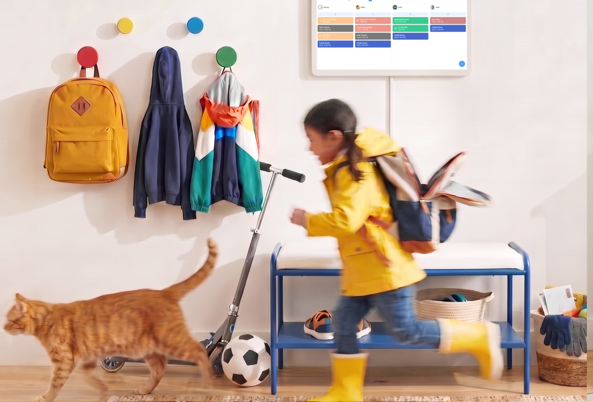 Home Hub wall-mounted in an entryway showing the shared calendar as a child runs out the door past the family cat
